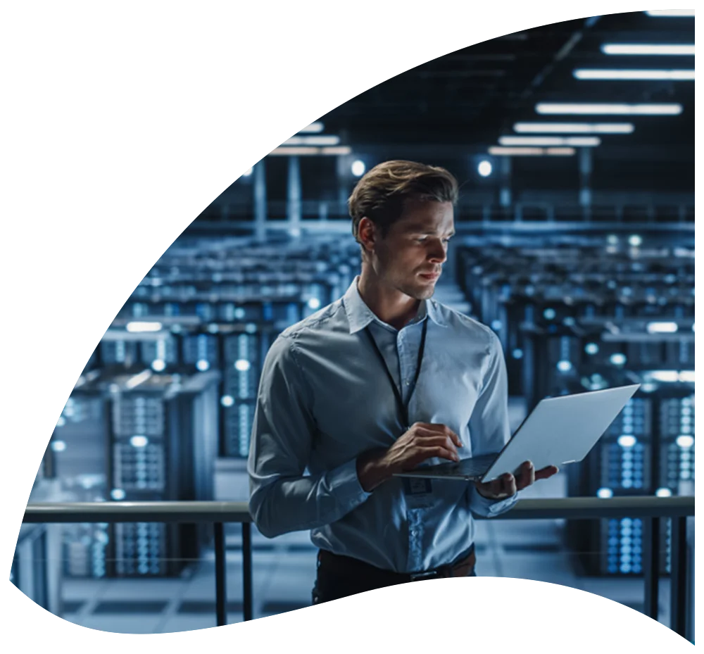 Visual of a man standing holding a laptop in a data center